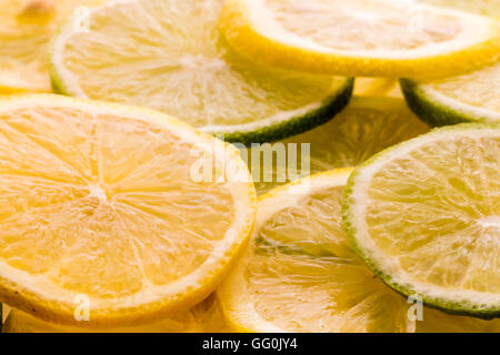 Limone e frutta di lime. Fette di entrambi, misti, impilati alla rinfusa. Top di lit. Foto Stock