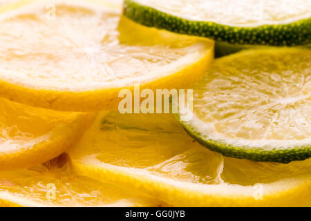 Limone e frutta di lime. Fette di entrambi, misti, impilati alla rinfusa. Top di lit. Foto Stock