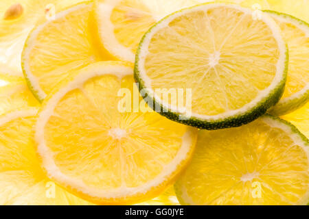 Limone e frutta di lime. Fette di entrambi, misti, impilati alla rinfusa. Back lit. Visto da sopra. Foto Stock