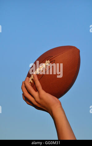 Quarterback gettando un americano di calcio contro un cielo blu Foto Stock