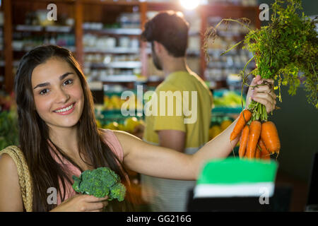 Donna acquisto mazzetto di carote e broccoli nel supermercato Foto Stock