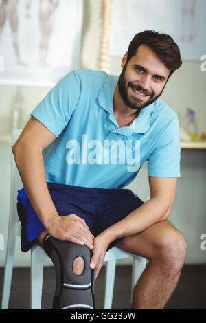 Ritratto di uomo sorridente con infortunio al ginocchio Foto Stock