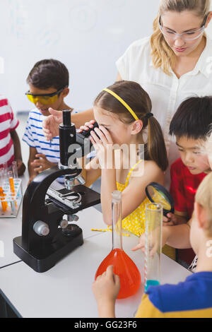 Schoolgirl guardando attraverso il microscopio in laboratorio Foto Stock