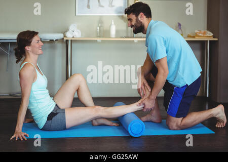 Fisioterapista facendo terapia della gamba per una donna usando il rullo di schiuma Foto Stock