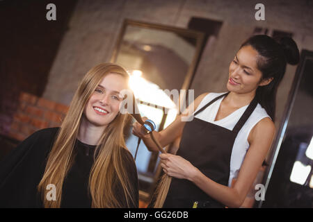 Parrucchiere femmina lisciare i capelli di un client Foto Stock