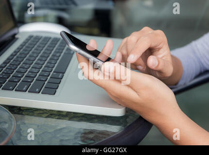 Chiudere la mano utilizzando il telefono sul tavolo di lavoro Foto Stock