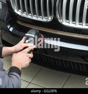 Il lavoratore lucidi un bumper car cruscotto con l'attrezzo elettrico. Close up Foto Stock