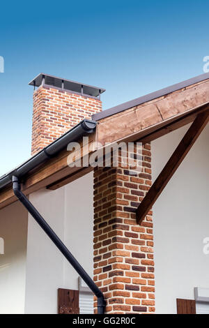Dettagli architettonici di casa residenziale: tetto grondaia, camino Foto Stock