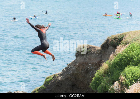 Un giovane adolescente tombstoning off scogliere in Newquay, Cornwall. Foto Stock