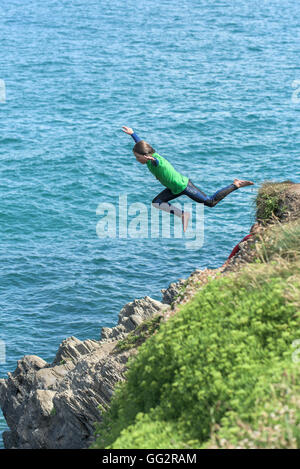 Un giovane adolescente tombstoning off scogliere in Newquay, Cornwall. Foto Stock