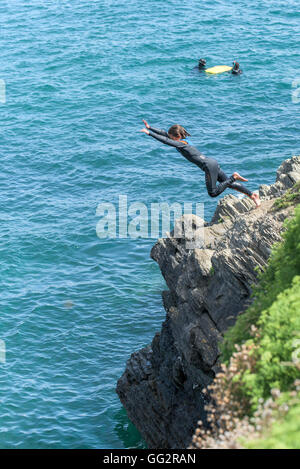 Un giovane adolescente tombstoning off scogliere in Newquay, Cornwall. Foto Stock