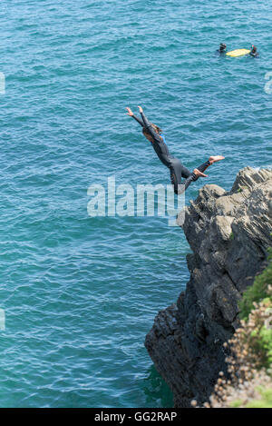 Un giovane adolescente tombstoning off scogliere in Newquay, Cornwall. Foto Stock