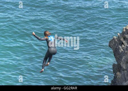 Un giovane adolescente tombstoning off scogliere in Newquay, Cornwall. Foto Stock