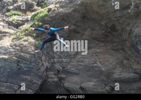 Un giovane adolescente tombstoning off scogliere in Newquay, Cornwall. Foto Stock