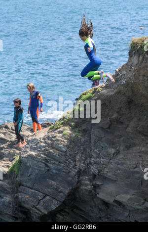 Un giovane adolescente tombstoning off scogliere in Newquay, Cornwall. Foto Stock