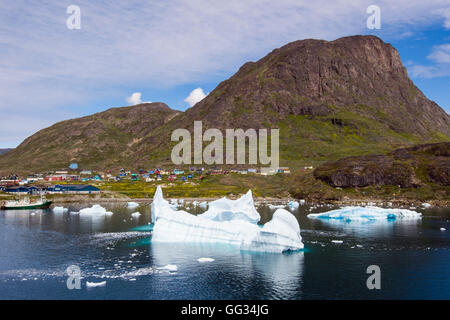 Iceberg dal fiordo Tunulliarfik galleggiante offshore con vista della città sottostante Qaqqarsuaq Fjeld montagna. Narsaq Kujalleq Groenlandia Foto Stock