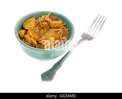 TV cena di angel hair pasta con le zucchine e gli spinaci in una piccola ciotola verde con una forcella per il lato su uno sfondo bianco. Foto Stock