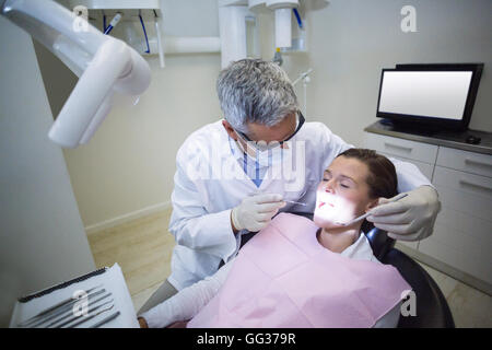 Dentista esamina un paziente con strumenti Foto Stock