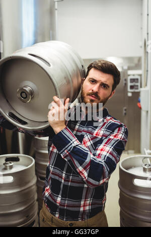 Produttore di sesso maschile che trasportano barile in fabbrica di birra Foto Stock