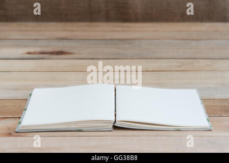 Libro aperto con pagine vuote sulla tavola di legno