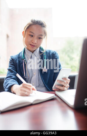 Medico donna utilizzando il telefono cellulare Foto Stock