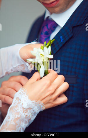 Appendere una sposa boutonniere di regolazione sulla camicia di sposi Foto Stock