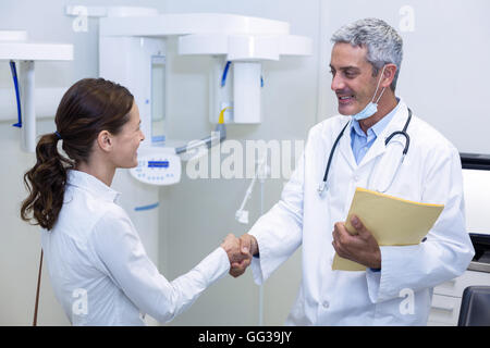 Dentista agitando la mano con paziente femmina Foto Stock