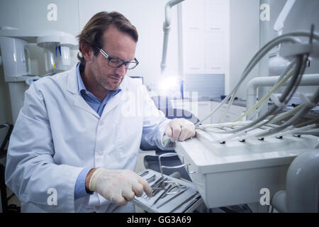 Dentista guardando strumento dentale Foto Stock