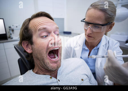 Paziente di sesso maschile spaventata durante un dentista di check-up Foto Stock