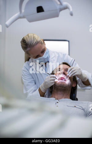 Dentista esamina un paziente con strumenti Foto Stock