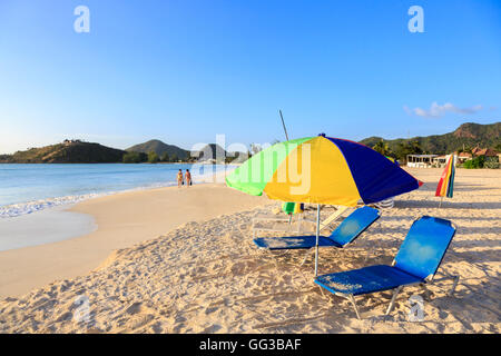 Sun ombrellone e lettini sulla spiaggia di sabbia dorata a Jolly Harbour, a sud-ovest di Antigua in una giornata di sole con cielo blu Foto Stock