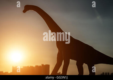 Silhouette di brachiosaurus ed edifici in tempo al tramonto Foto Stock