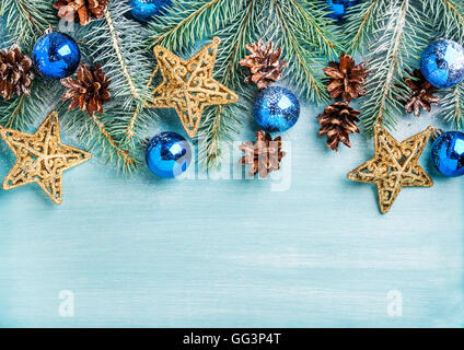 Anno nuovo o sfondo di Natale: rami d abete, blu delle palline di vetro, coni, stelle dorate su turchese sullo sfondo di legno, spazio di copia Foto Stock