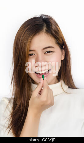 Bella donna asiatica tenendo un pillola contro uno sfondo bianco. Foto Stock