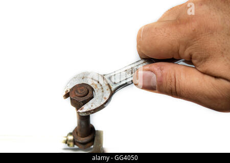Lavoratore mano serrando o allentando il dado di un bullone arrugginito con una chiave su sfondo bianco Foto Stock