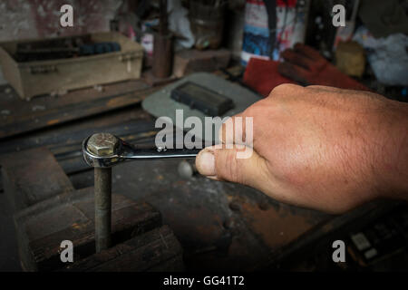 Lavoratore mano serrando o allentando il dado di un bullone arrugginito con una chiave Foto Stock
