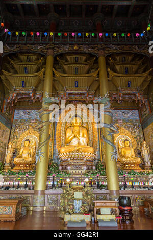 Tall Dharma Hall e tre Golden Statue di Buddha all'interno del Yakchunsa (Yakcheonsa) tempio sulla isola di Jeju in Corea del Sud. Foto Stock