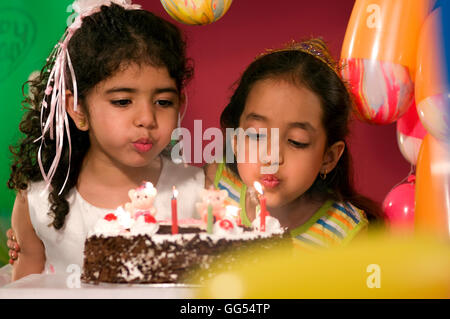 Due ragazze soffiando fuori candele Foto Stock