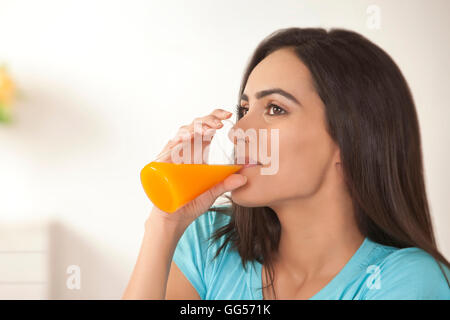Giovane donna di bere un bicchiere di succo di frutta fresco a casa Foto Stock