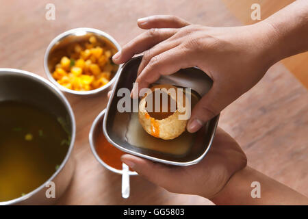 Immagine ritagliata dell'uomo azienda golgappa nel recipiente Foto Stock