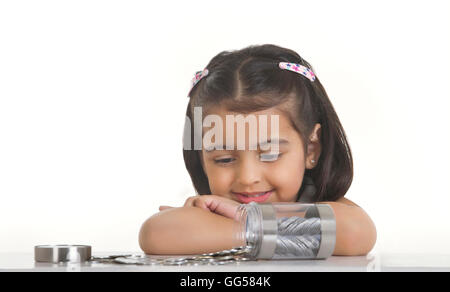 Ragazza guardando le monete indiano versato sul tavolo contro uno sfondo bianco Foto Stock