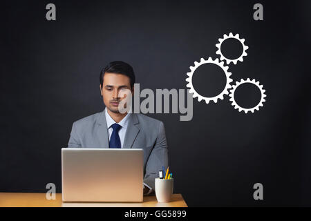 Generati digitalmente immagine dell uomo d affari utilizzando il portatile in ufficio con ingranaggi Foto Stock