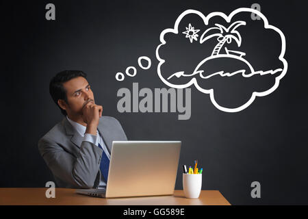 Giovane imprenditore indiano pensando di vacanza durante il lavoro Foto Stock