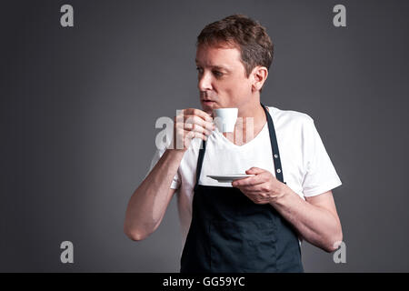 Un Medioevo uomo con una tazza di caffè e guardando lontano sospetto Foto Stock