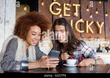 Amici di sesso femminile utilizzando uno smart phone con caffè al caffè