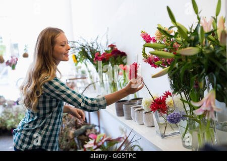 Il profilo laterale di una donna tenendo un fiore e sorridente Foto Stock
