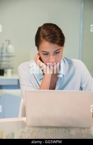 Bella imprenditrice che guardano un notebook in un ufficio Foto Stock