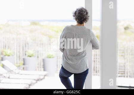 Vista posteriore di una donna appoggiata ad una colonna Foto Stock