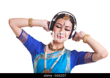Danzatrice Bharatanatyam ascoltando la musica attraverso le cuffie su sfondo bianco Foto Stock
