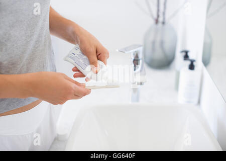 Donna che strizza dentifricio dal tubo allo spazzolino vicino al lavandino  in bagno, primo piano Foto stock - Alamy